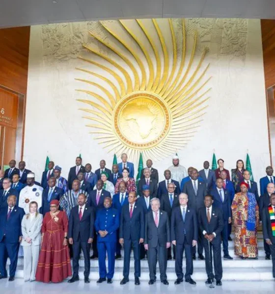 A wide-angle portrait of African Heads of State and international dignitaries, including UN Secretary-General António Guterres and Italian Prime Minister Giorgia Meloni, posing for the official family photo at the 39th African Union Summit in Addis Ababa to discuss African Union strengths and weaknesses. The leaders are gathered in the lobby of the Nelson Mandela Plenary Hall in front of the large golden AU emblem wall.