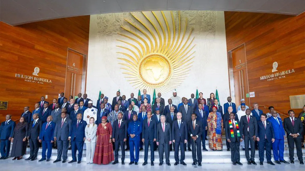 A wide-angle portrait of African Heads of State and international dignitaries, including UN Secretary-General António Guterres and Italian Prime Minister Giorgia Meloni, posing for the official family photo at the 39th African Union Summit in Addis Ababa to discuss African Union strengths and weaknesses. The leaders are gathered in the lobby of the Nelson Mandela Plenary Hall in front of the large golden AU emblem wall.